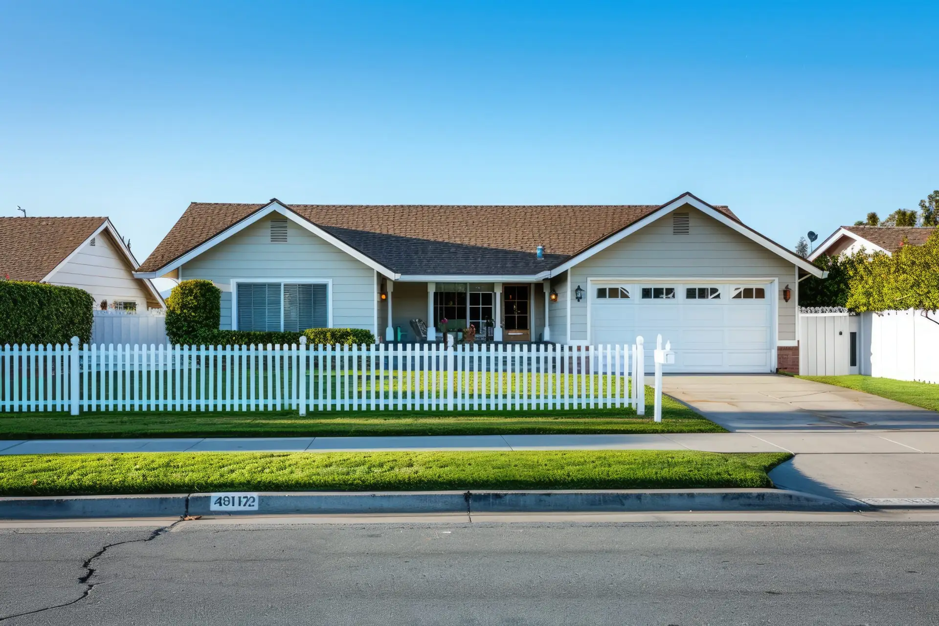 Charming single-story Texas Real Estate home with white siding, brown roof, attached double garage, inviting front porch with chairs, white picket fence, and a manicured lawn—perfect for your next home inspection.