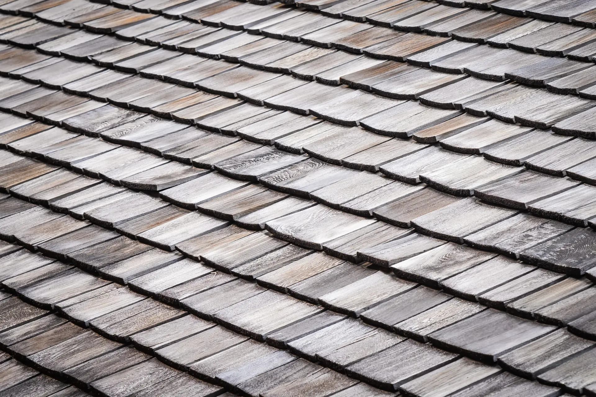 Close-up view of overlapping weathered wooden shingles on a roof, displaying various shades of gray and brown—an important detail for any Houston home inspector.
